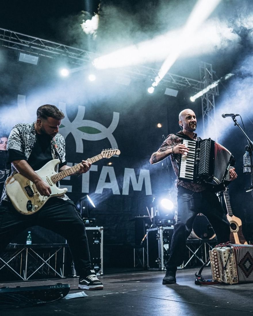 Alessio alla chitarra con gli Zeketam, su un palco con luci bianche e fumo